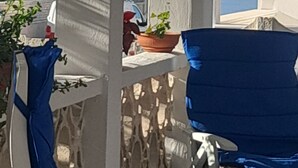 A covered outdoor seating area with a view of the sea, featuring a blue chair and a white table. - Sea view cottage (San Pietro In Bevagna)