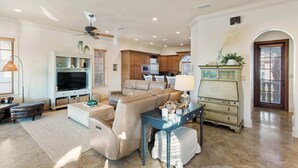 Un salón amplio con un sofá de cuero grande, un televisor y un comedor con mesa y sillas.