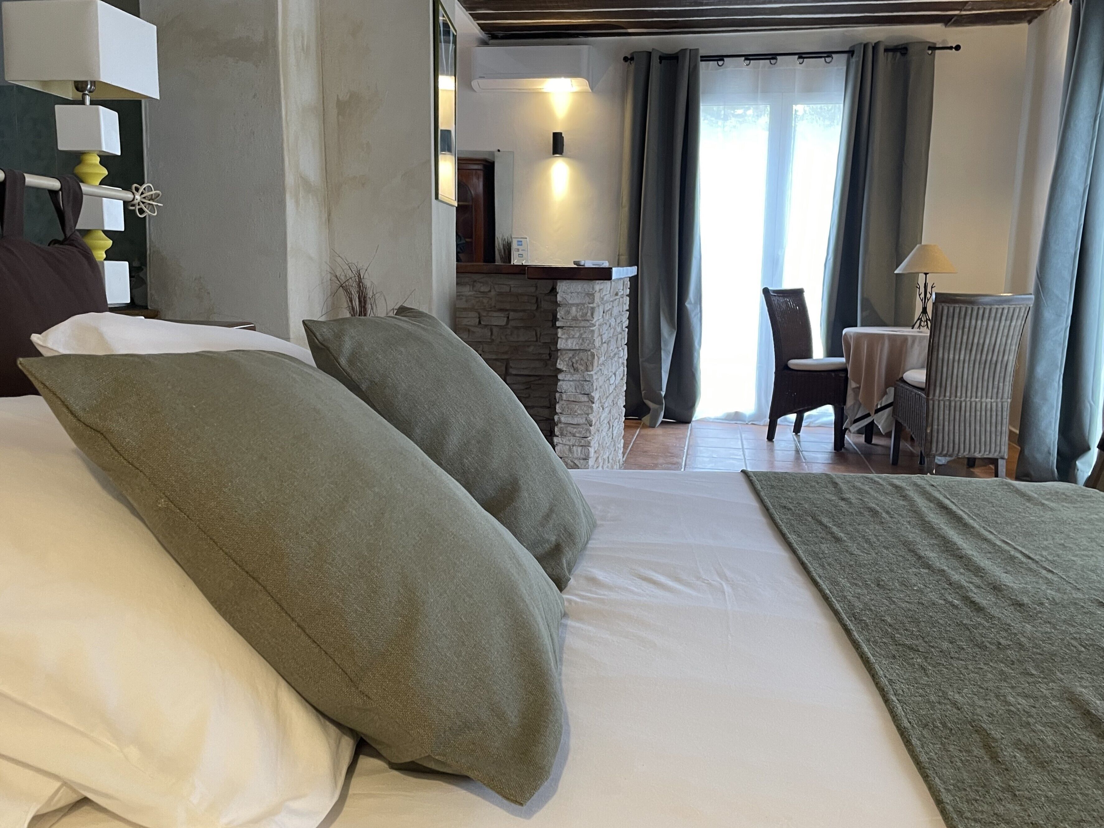 Un dormitorio con una cama grande, una chimenea de piedra, un comedor con mesa y sillas, y vistas al exterior.