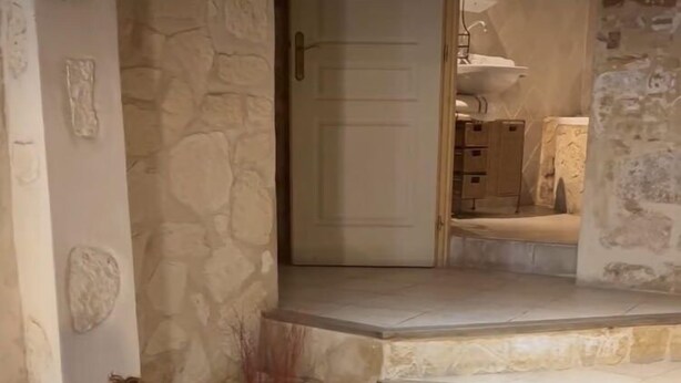 A stone-walled room with a bed, a massage table, and a small table with candles. - In Provence Hôtel (Venelles)