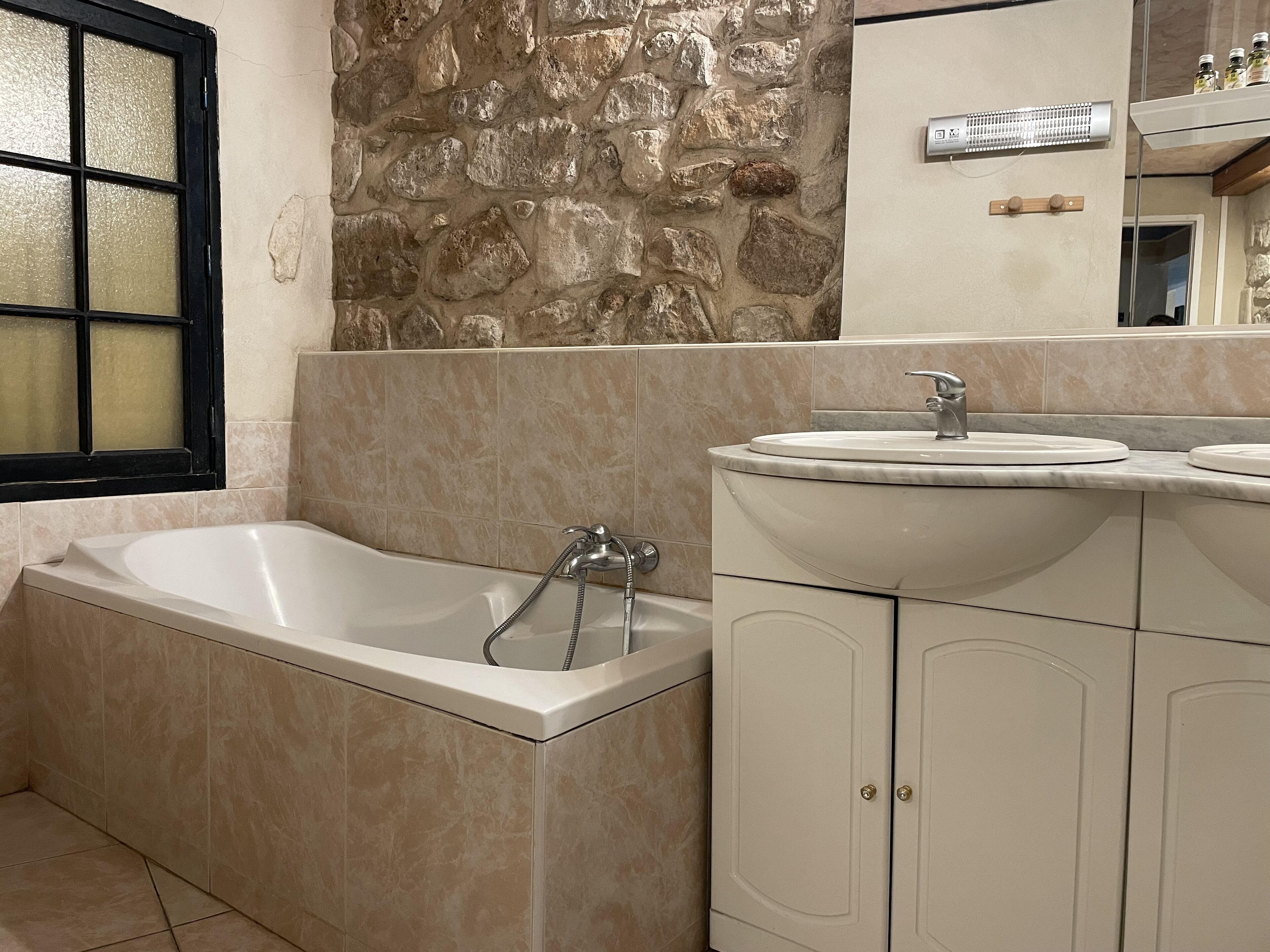 A bathroom with a bathtub, a sink, and a stone wall.