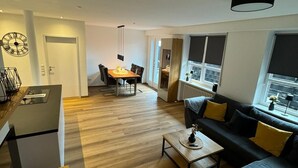 A modern living room with a sofa, coffee table, and dining area.