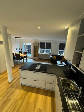 A modern kitchen with a central island, built-in appliances, and a dining area with a table and chairs.