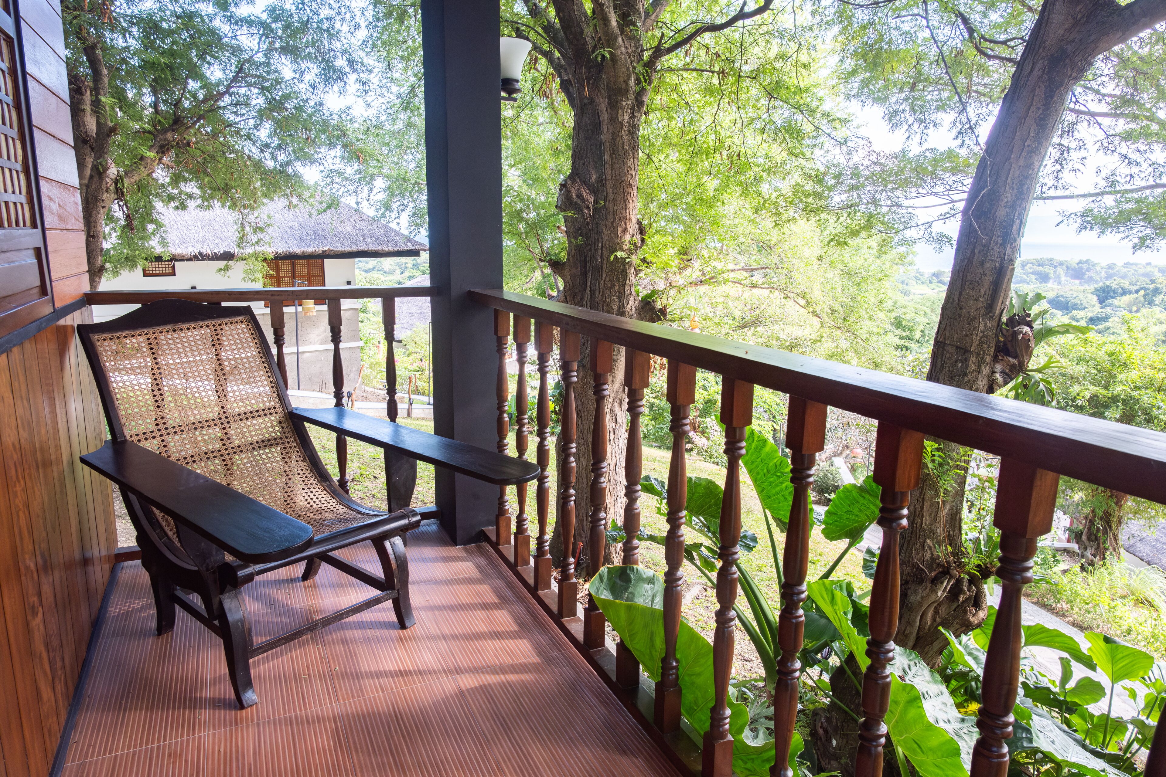 Une terrasse en bois, agrémentée d’un banc et d’une balustrade, qui offre une vue sur un paysage verdoyant et luxuriant.