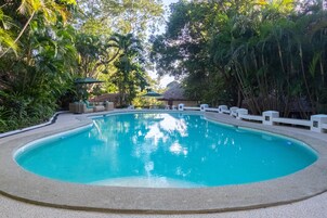 Una piscina al aire libre, sombrillas, sillones reclinables de piscina