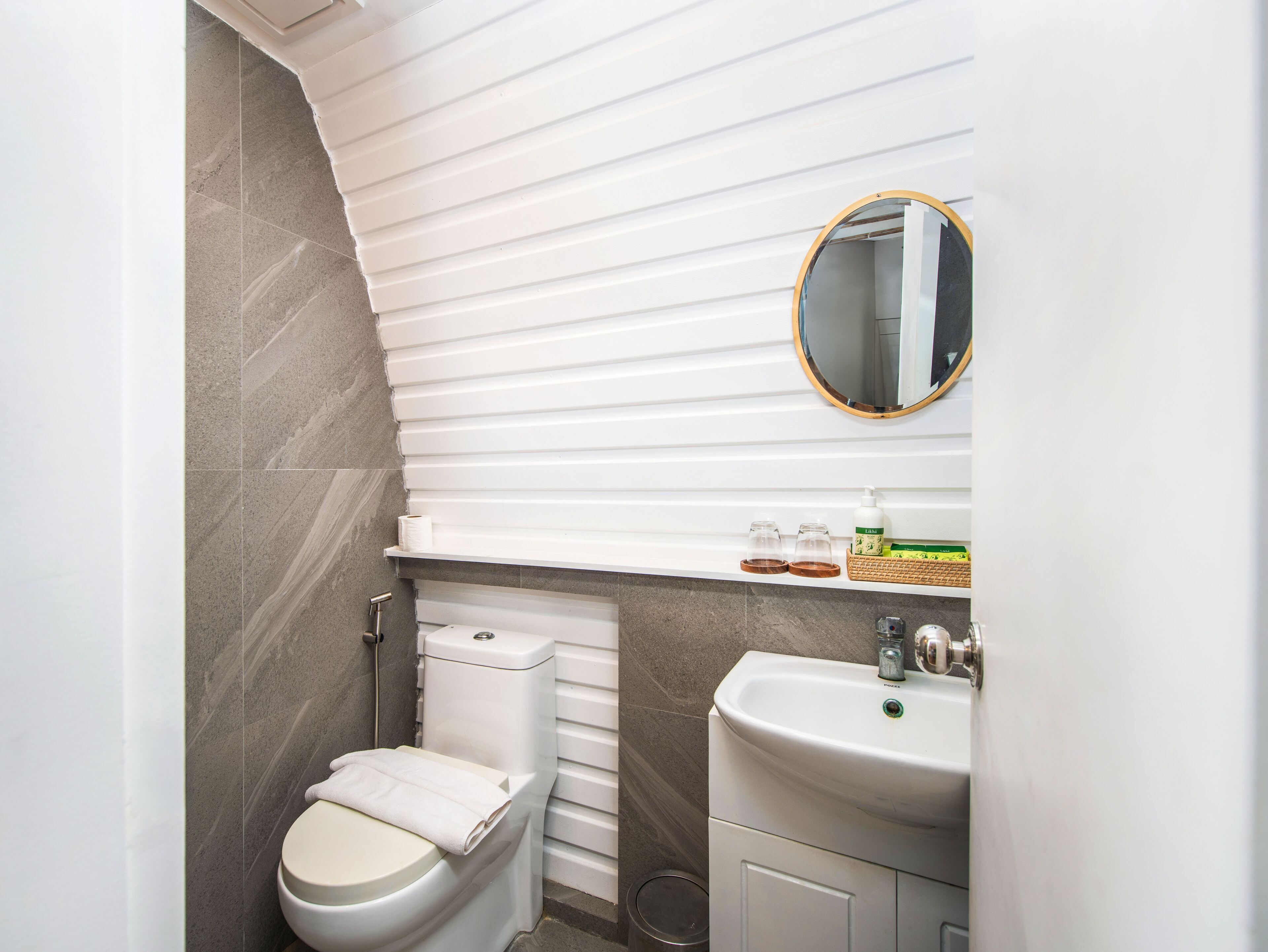 Een kleine badkamer met toilet, wastafel en spiegel.