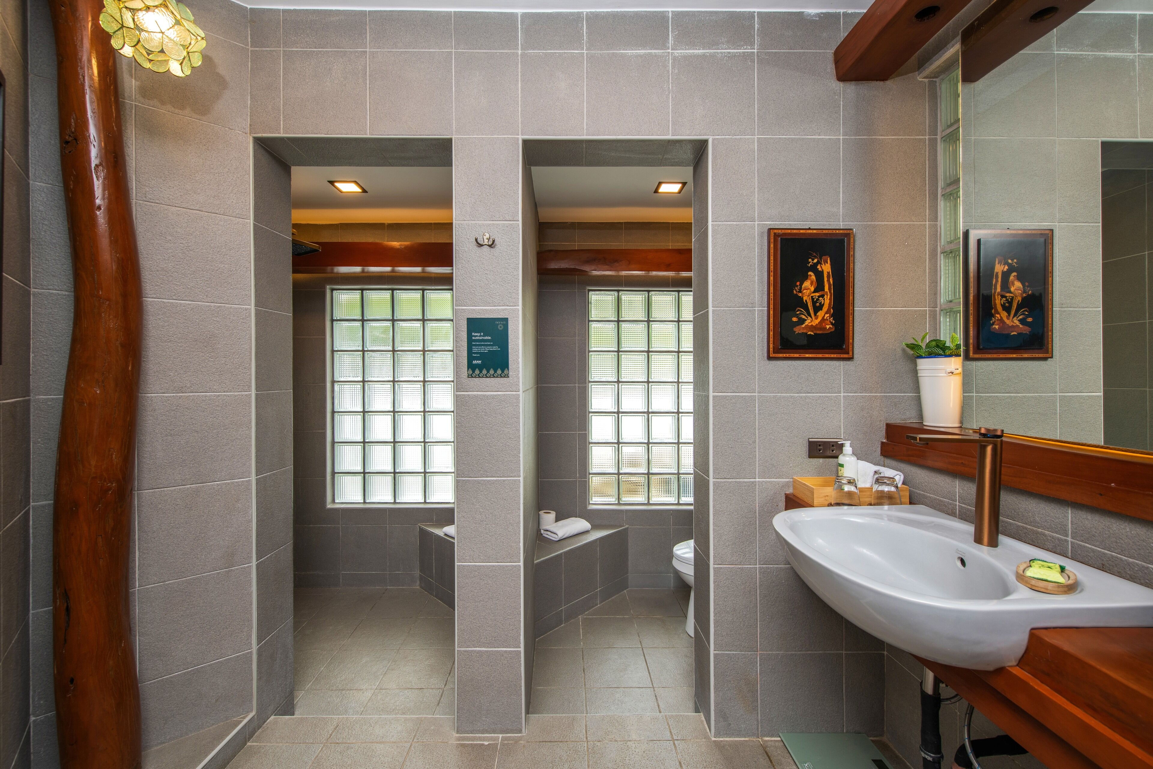 A modern bathroom with a large sink, two windows, and a wooden accent wall.