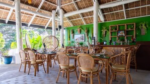 Un restaurant doté de mobilier en bambou, d’un mur végétal et d’un toit de chaume.