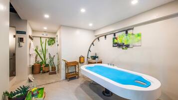 A modern bathroom with a large bathtub, a steam sauna sign, and decorative plants.