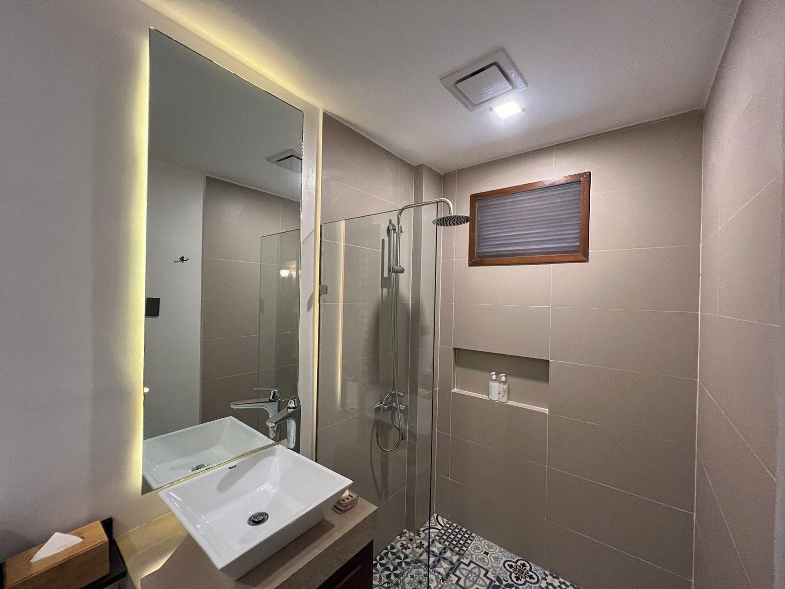 A modern bathroom with a glass-enclosed shower, a white sink, and a large mirror.
