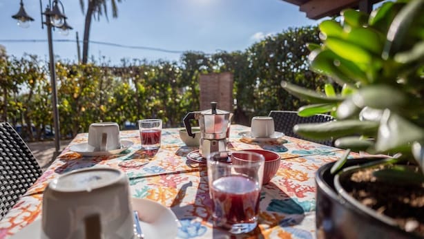An outdoor table set with a coffee maker, cups, and a potted plant. - Apartment 50 meters from the sea in Taormina, with free private parking (Mazzeo)