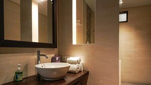 Une salle de bain avec un grand miroir, un lavabo blanc et un flacon de savon pour les mains.