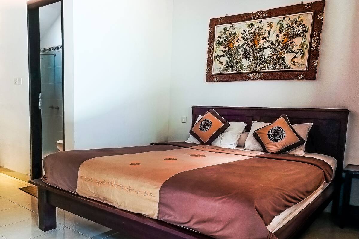 A bed with a brown and beige bedspread, two decorative pillows, and a wooden headboard.