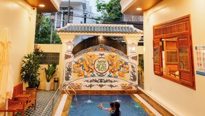 A swimming pool with a decorative wall and a small bridge. - 75 Garden INN (Hue)