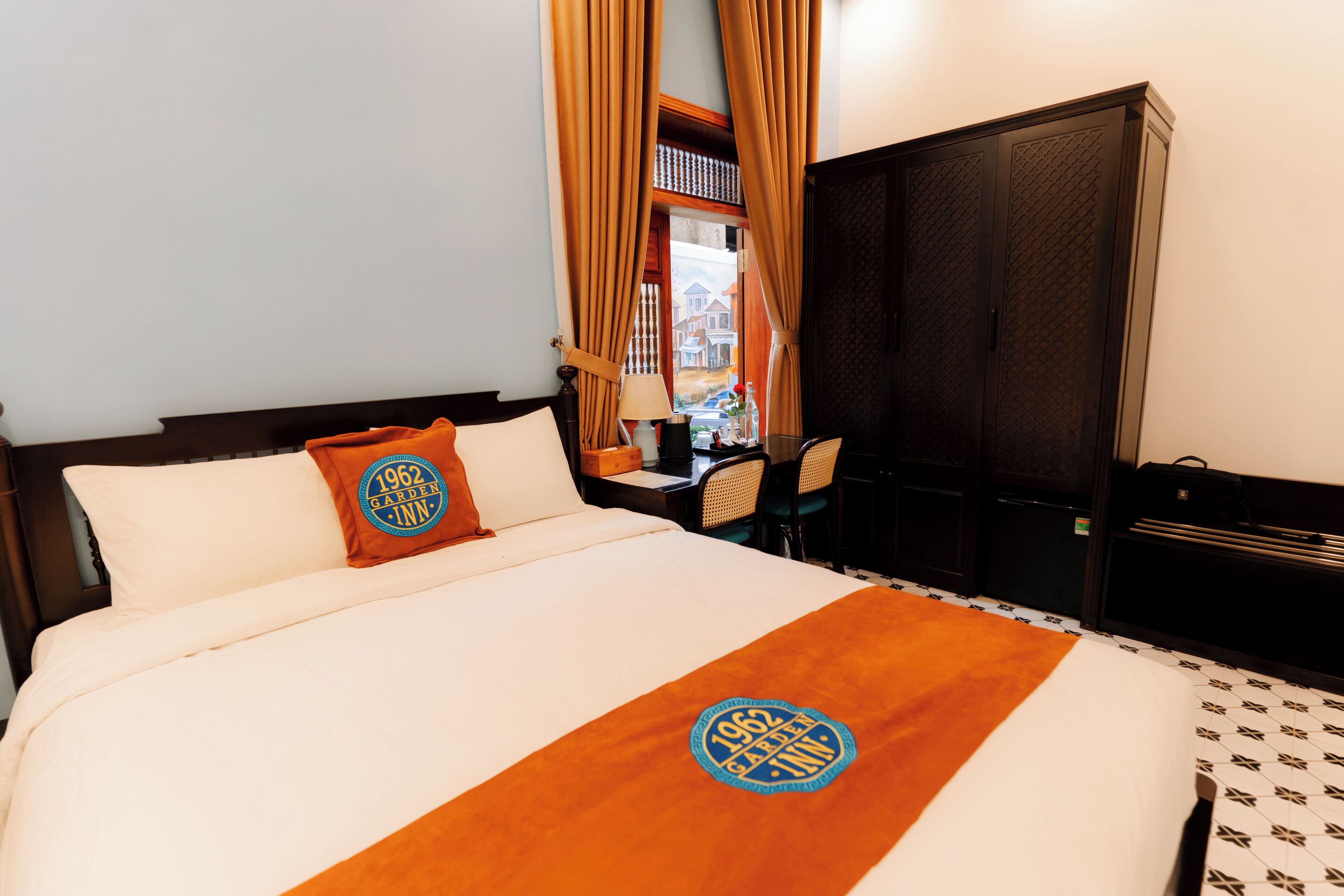 A hotel room with a bed, a desk, and a wardrobe.