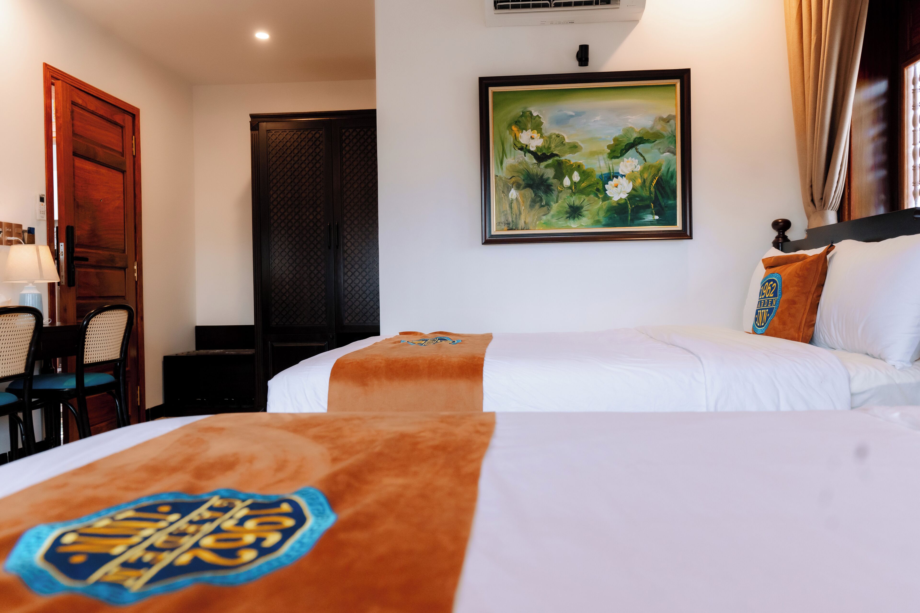 Ein Hotelzimmer mit zwei Betten, einem Bild an der Wand und einer Tür.