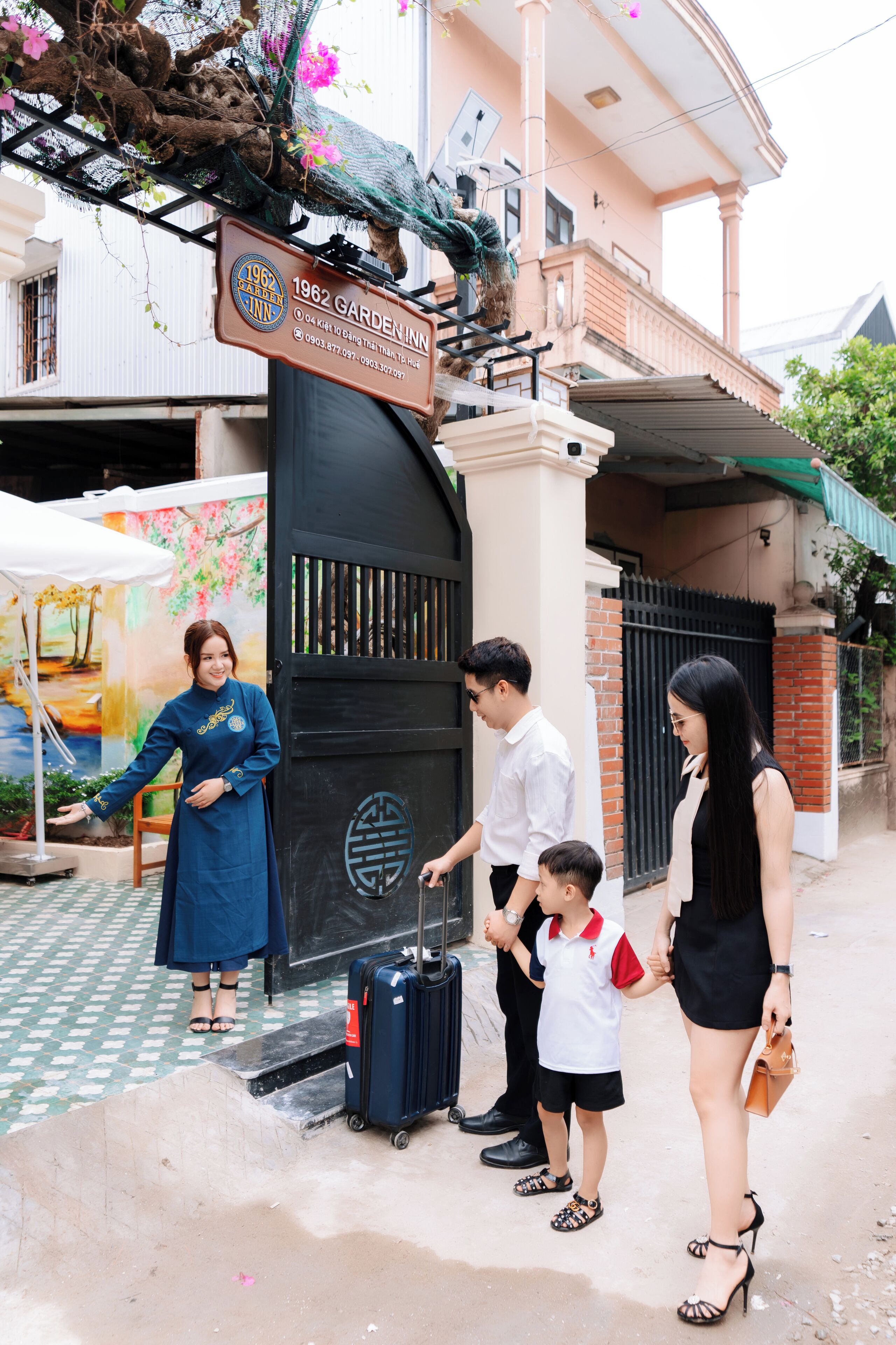 A family standing in front of a building with a sign that reads "1962 GARDEN INN."