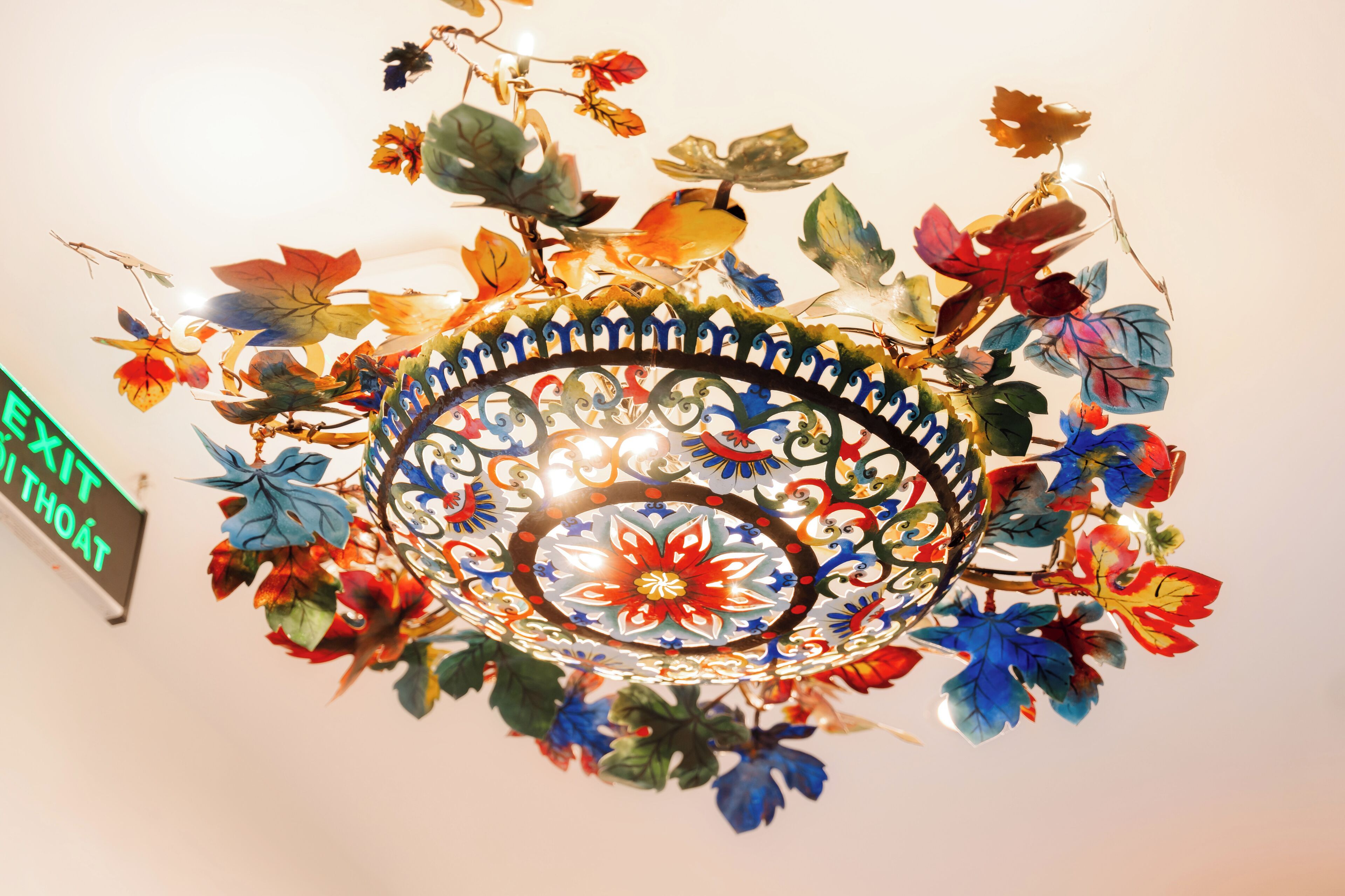 A ceiling with a decorative metal spiral and colorful artificial leaves.