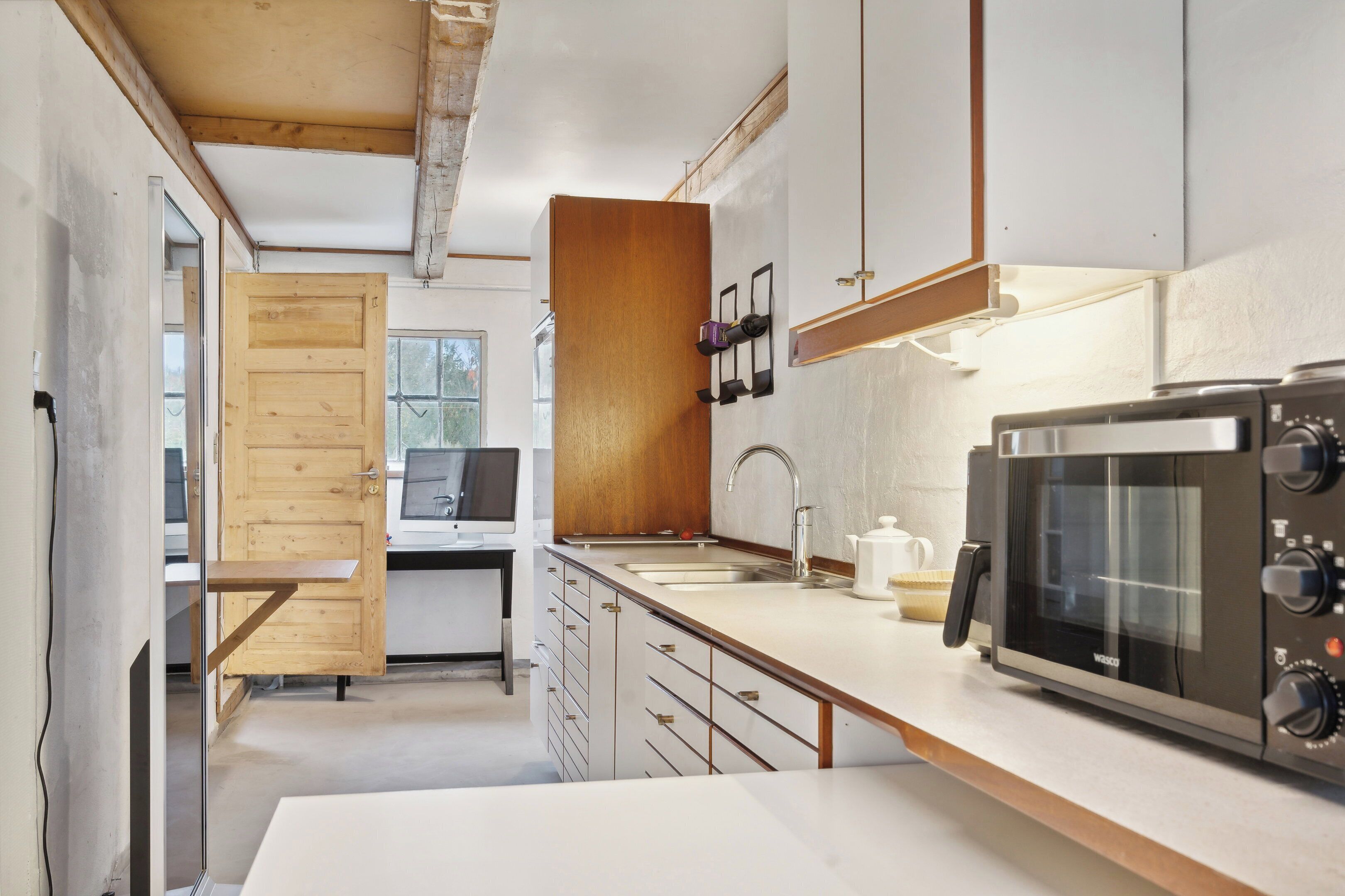 Une cuisine moderne équipée d’un four à micro-ondes, d’un évier, de meubles de rangement en bois et d’une porte en bois.