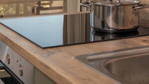 Een moderne keuken met uitzicht op zee, een houten wand en een pan op het fornuis.