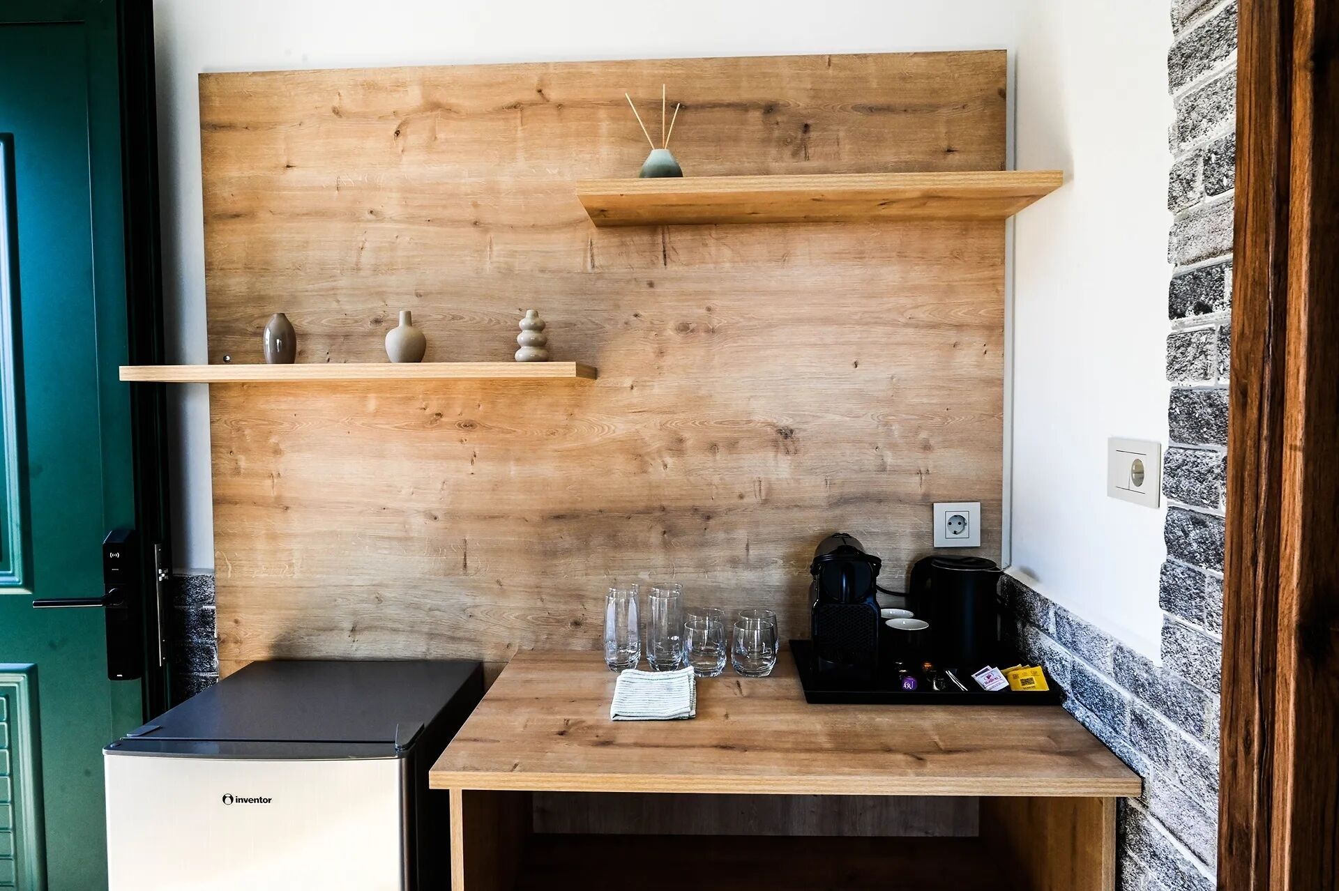 Eine kleine Küche mit Holzwand, einem kleinen Kühlschrank und einer Kaffeemaschine.