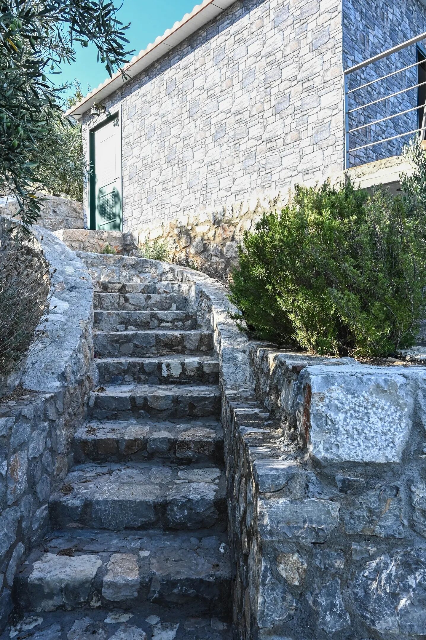 Un escalier en pierre mène à un bâtiment dont la façade et la porte sont également en pierre.
