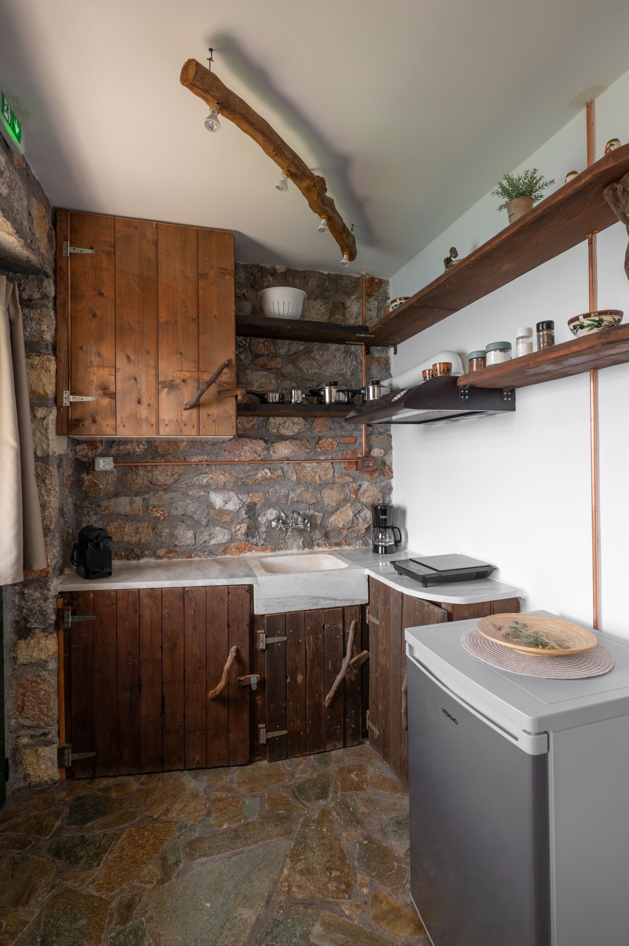 Een landelijke keuken met houten kastjes, een stenen muur en een ingebouwd spoelgedeelte.