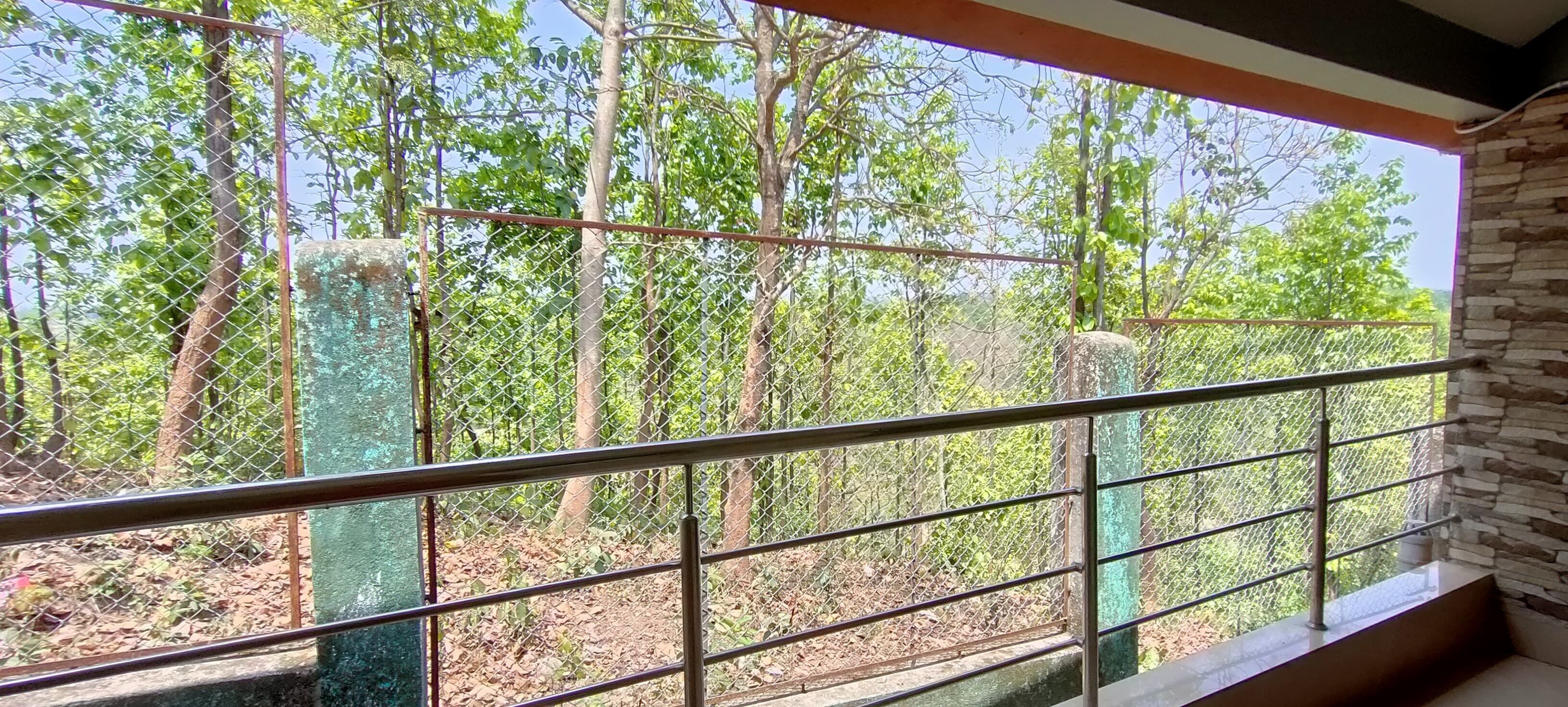 A room with a view of a forest through a metal fence.