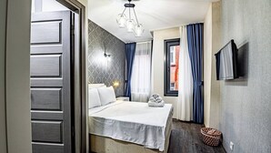 A hotel room with a bed, a television, a ceiling light fixture, and a window with curtains. - Room-deluxe Double Room 4 (Istanbul)