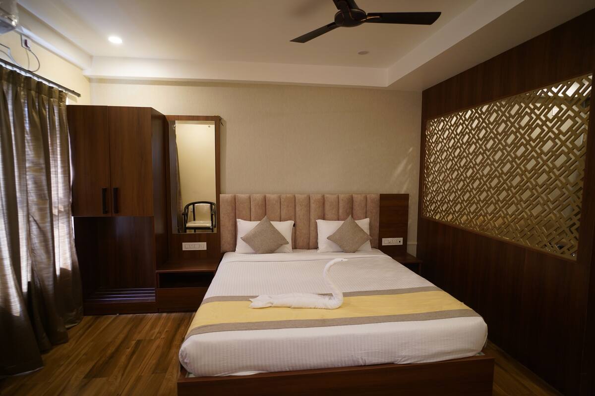 A hotel room with a large bed, wooden headboard, and a decorative wall panel.