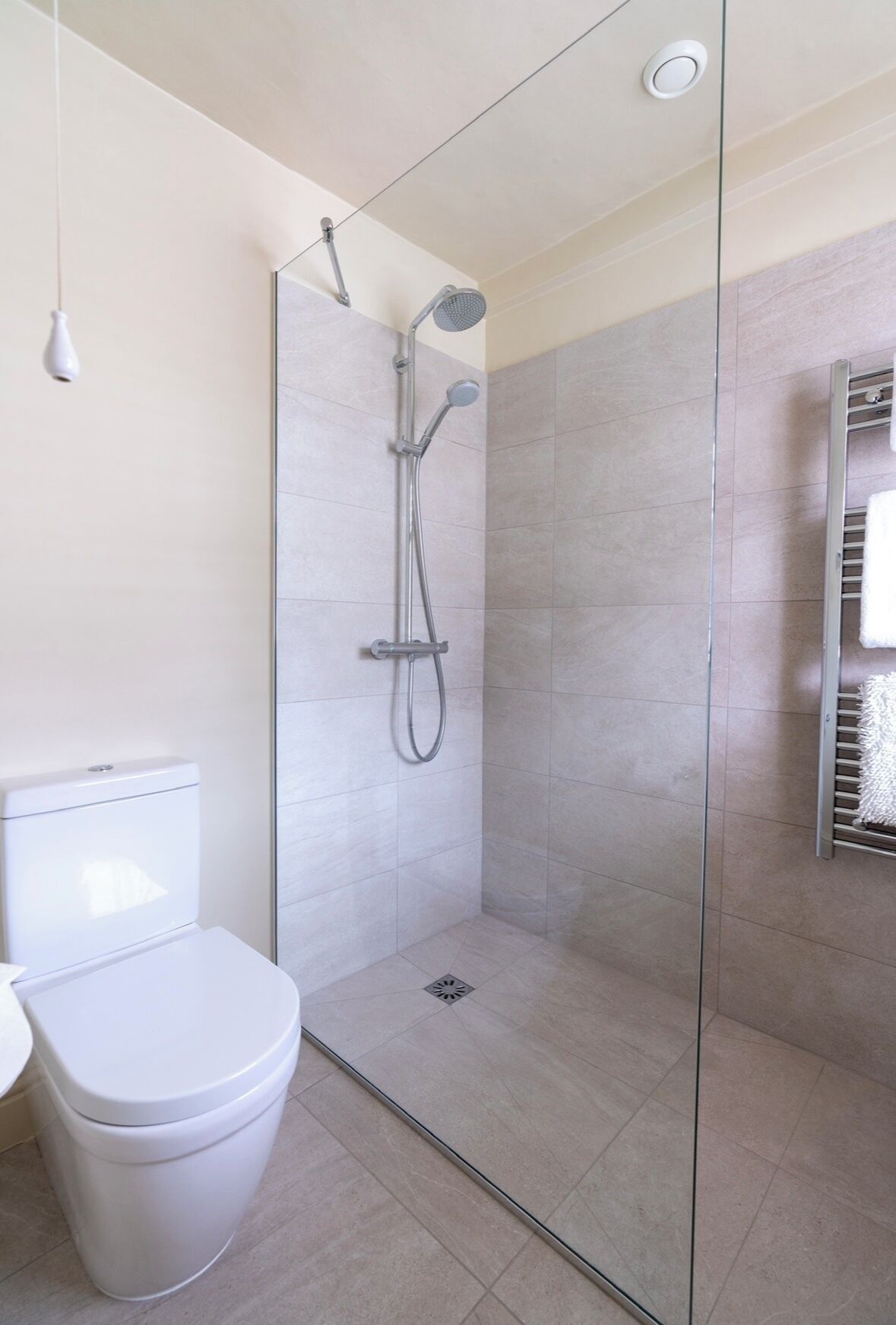 Un baño moderno con ducha de vidrio, inodoro blanco y barra para toallas.
