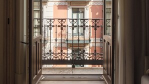 An open door leading to a balcony with a wrought iron railing, a view of a building with balconies, and a light-colored floor mat. - Líbere Bilbao Ledesma (Bilbao)