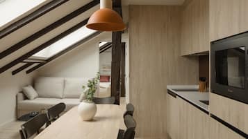 Una cocina moderna con comedor, que incluye una mesa de madera, sillas, un jarrón grande y un televisor fijado en la pared.