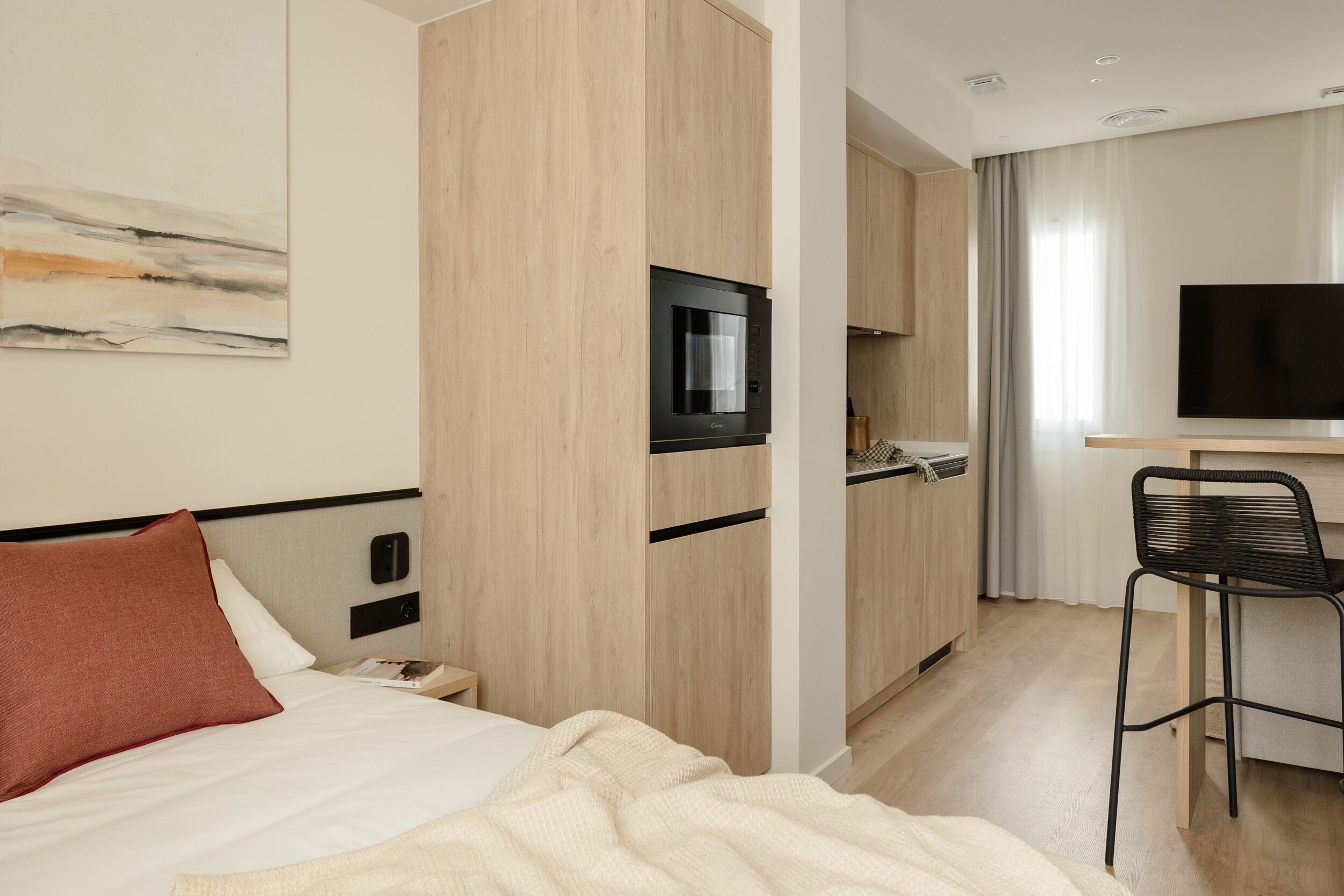 Ein Hotelzimmer mit Bett, Fernseher, Schreibtisch und Stuhl.