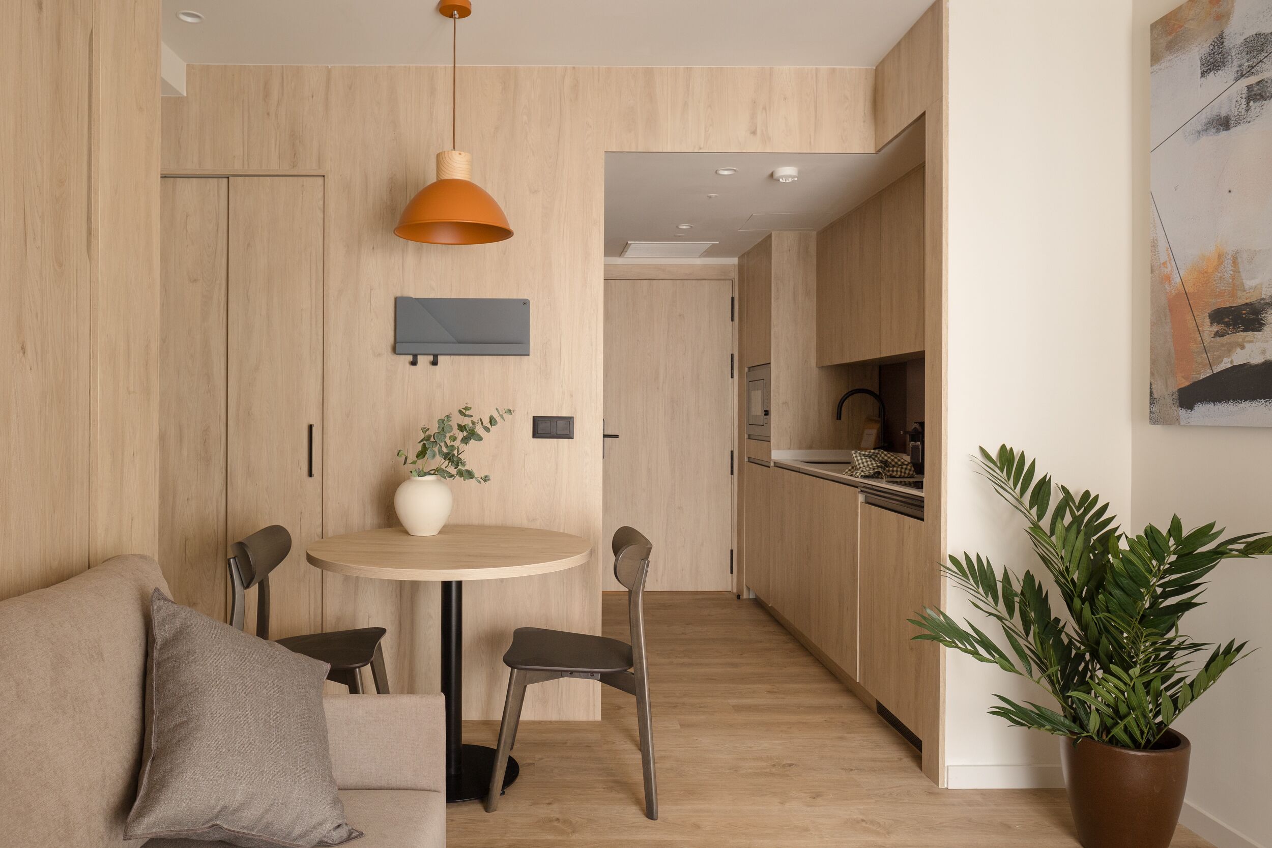 Une cuisine moderne avec des meubles en bois, une table à manger ronde et une plante en pot.