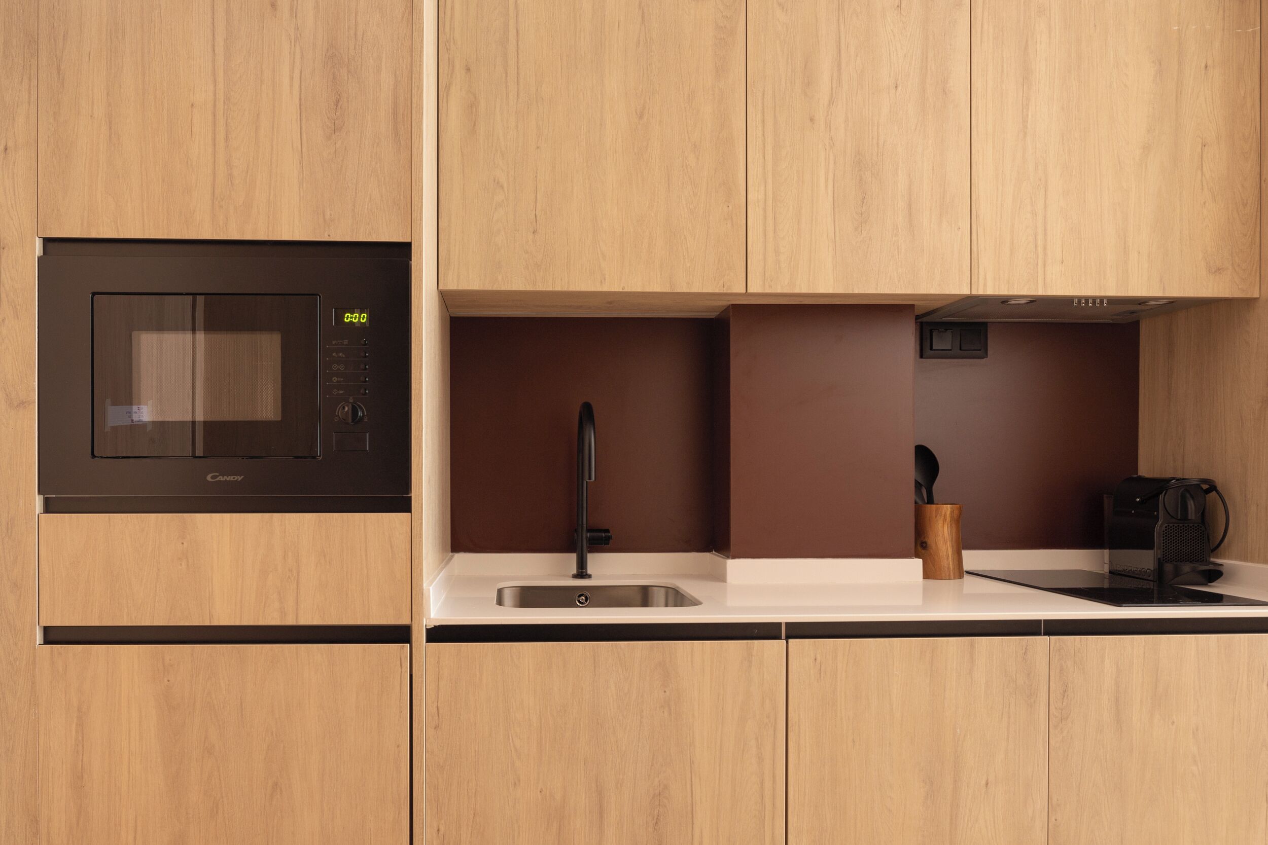 A modern kitchen with a built-in microwave, a sink, and wooden cabinetry.