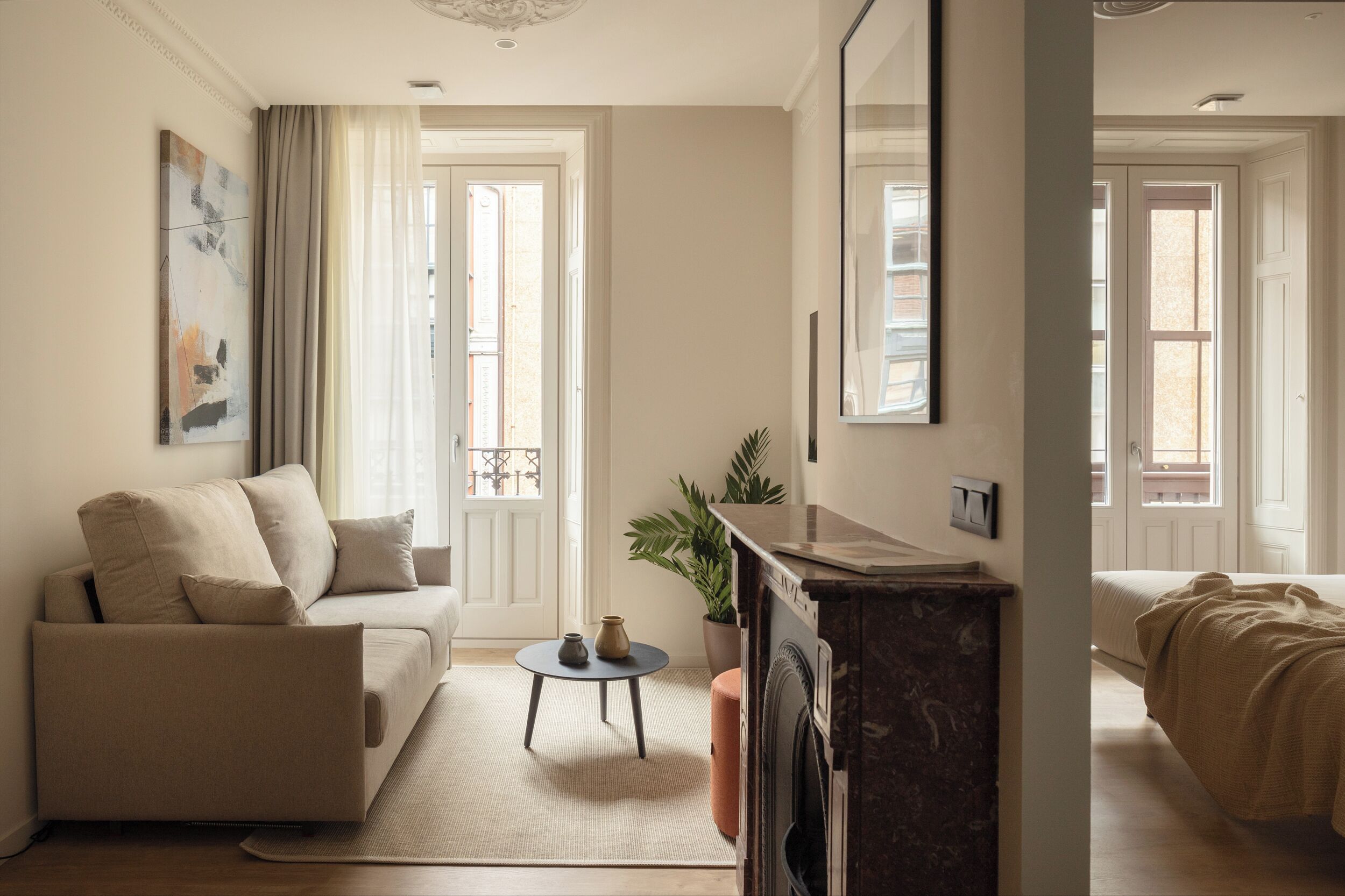 Een moderne woonkamer met een bank, een bijzettafeltje, een potplant en een open haard.