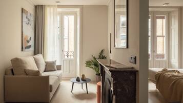 Een moderne woonkamer met een bank, een bijzettafeltje, een potplant en een open haard.