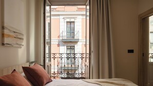 A hotel room with a bed, a window with curtains, and a view of a building with balconies. - Líbere Bilbao Ledesma (Bilbao)