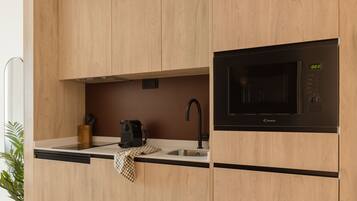 A modern kitchen with wooden cabinets, a built-in microwave, a sink, and a coffee maker.