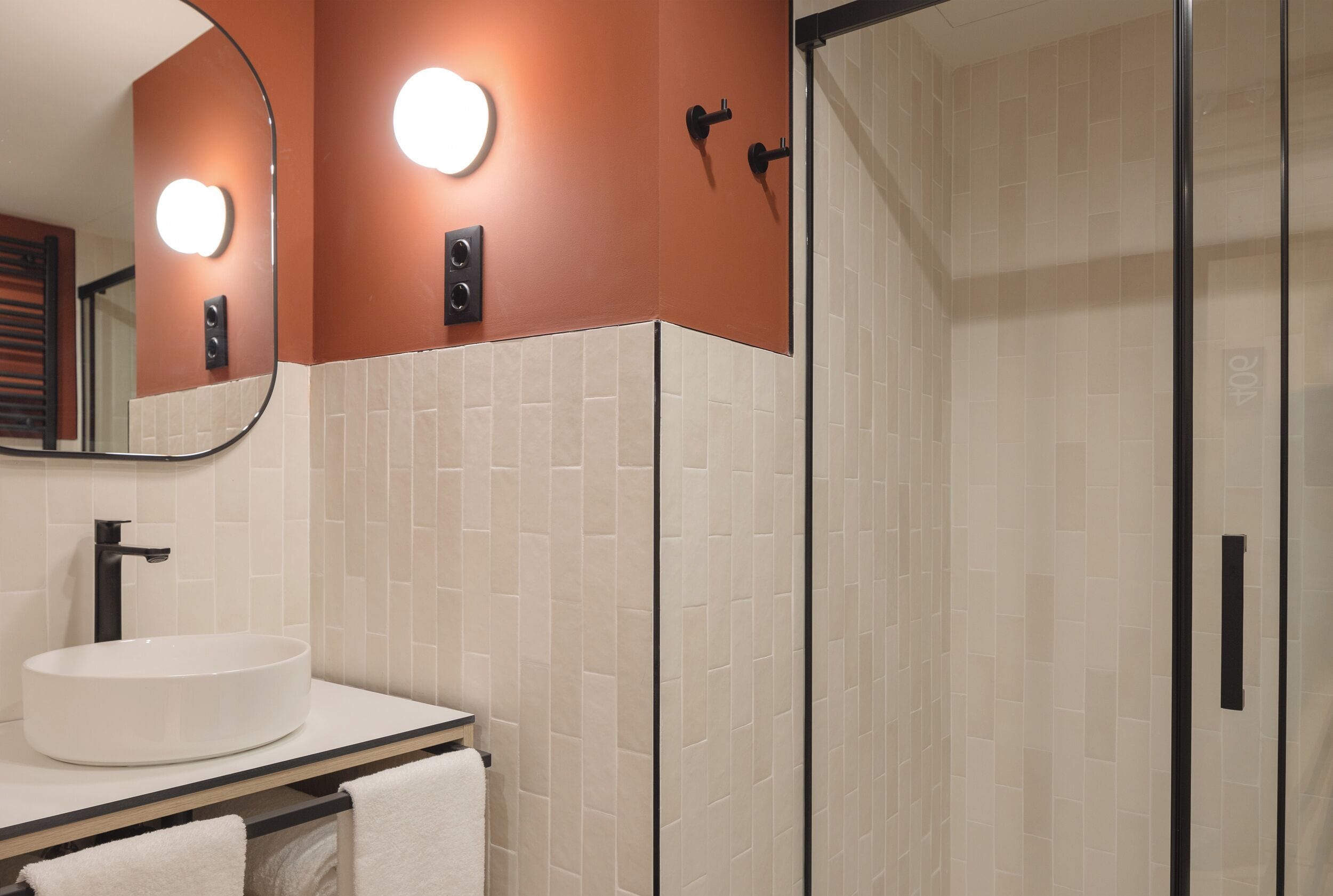 A bathroom with a round sink, a mirror, and a shower area.