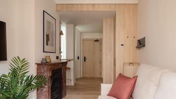 Una sala de estar con chimenea, un sofá blanco y un cojín rojo.