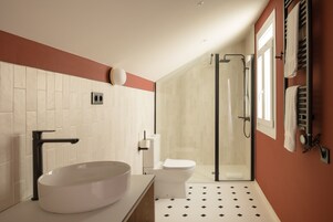 Un baño moderno con un lavabo de pedestal grande, un inodoro y una ducha con cerramiento de vidrio.