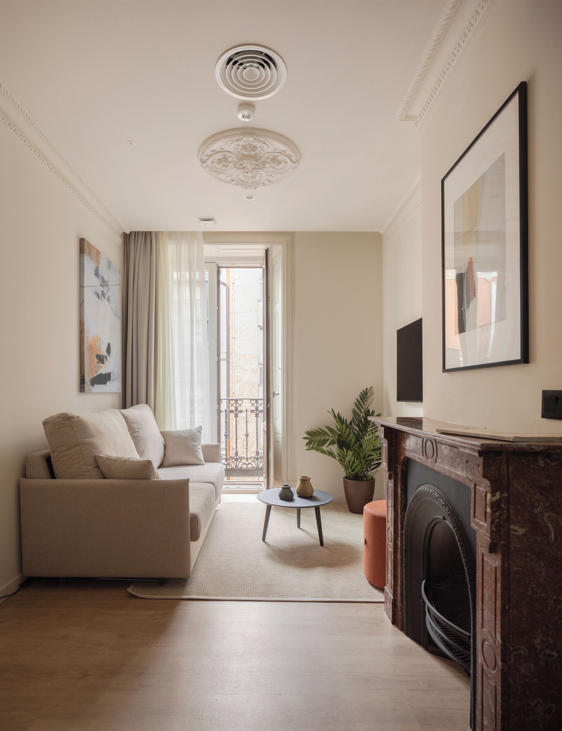 Ein modernes Wohnzimmer mit einer Couch, einem kleinen runden Tisch, einem Blumentopf und einem Kamin.
