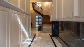 A grand hallway with a marble floor, a staircase, and a chandelier. - Líbere Bilbao Ledesma (Bilbao)
