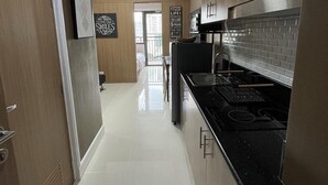 A modern kitchen with wooden cabinets, a black countertop, and a tiled backsplash. - 1 BR Fully Furnished Condo in Makati with Pool and Parking - Red Res. Unit 1133 (Makati)