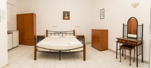 Un dormitorio con cama, armario de madera, cómoda y espejo.