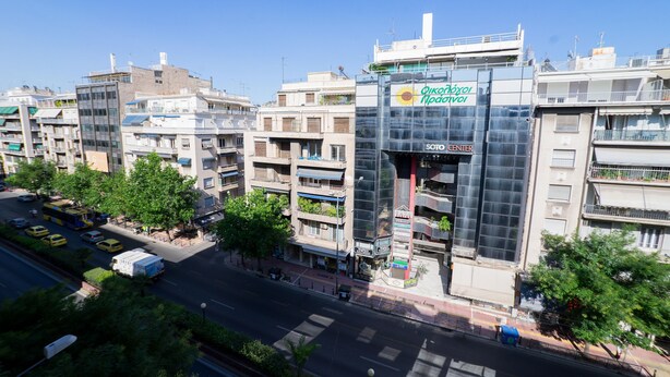 Un bâtiment moderne doté d’une façade en verre, d’une entrée bien visible et d’une enseigne indiquant « Oikonomio Piraei ».