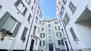 Une rue étroite en milieu urbain, bordée d’immeubles à plusieurs étages dotés de balcons et de fenêtres.