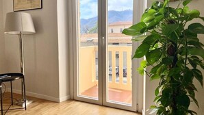 Une pièce dotée d’une porte-fenêtre coulissante donnant sur un balcon, d’une plante en pot et d’une lampe.